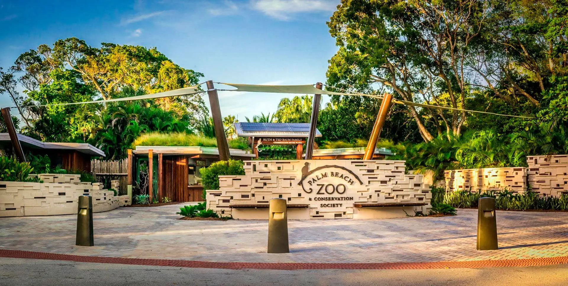 Entrance to Palm Beach Zoo and Conservation Society, featuring modern architectural design with surrounding greenery and stone pathway.